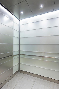 FSRT727 Интерьер лифта Levele-103 с индивидуальной компоновкой панелей; панели из вивихромового хромового стекла с прослойкой индивидуального цвета и отделкой opalex, а также из нержавеющей стали с отделкой из песчаника; квадрантные поручни в корпоративно Forms-surfaces 